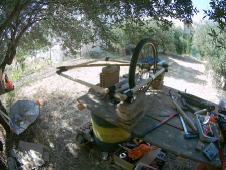 The frame, with one wheel mounted, on the workbench. Supported on brocks, ready for mounting the other wheel.